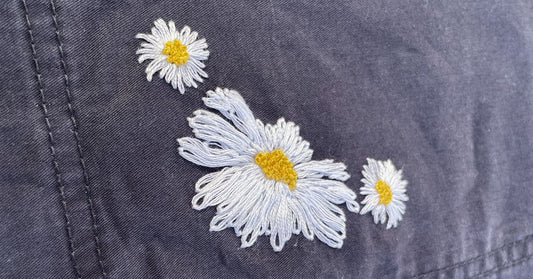 Embroidered ox eye daisy and common daisies on blue trouser pocket