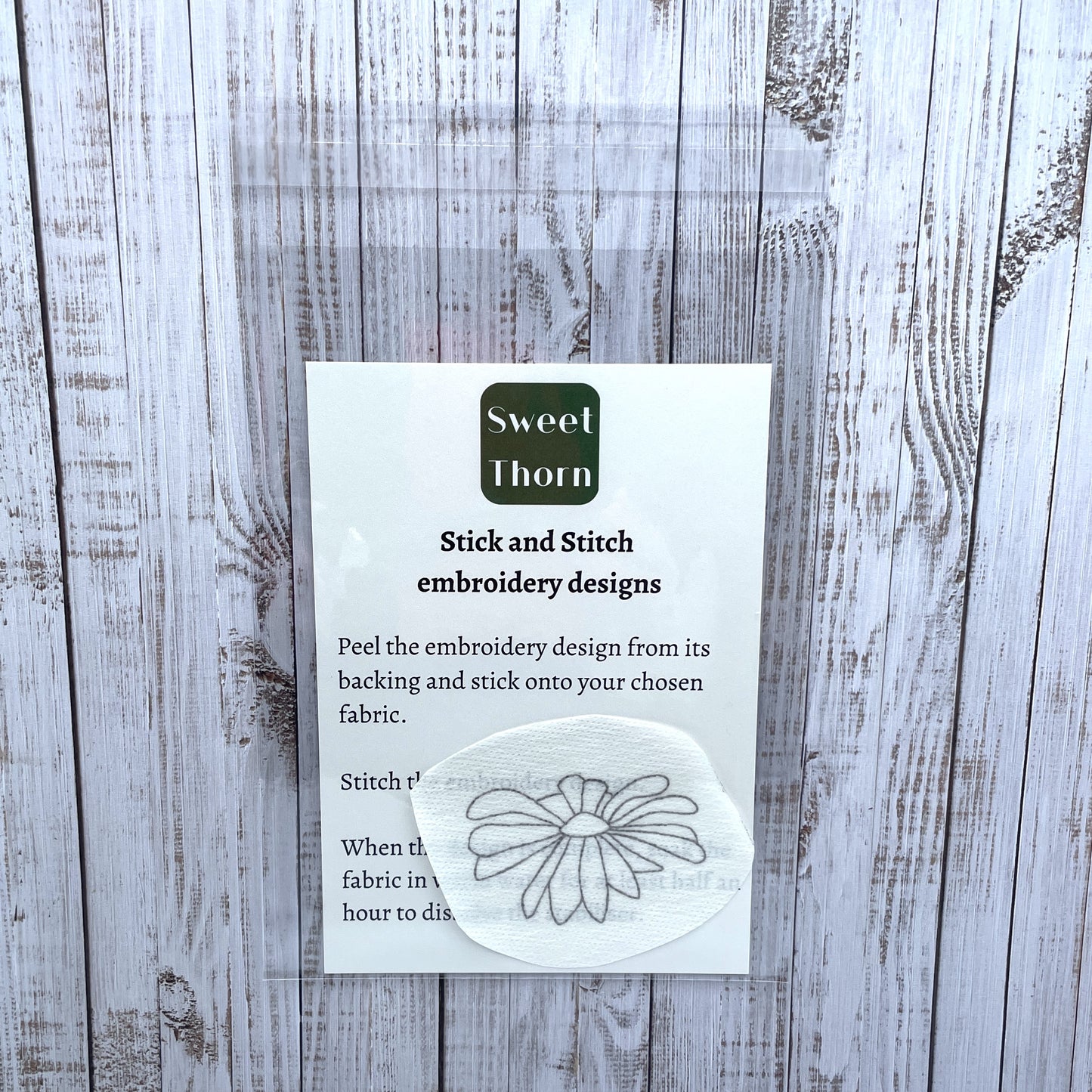 Daisy flower head embroidery sticker in cellophane bag with instructions card.