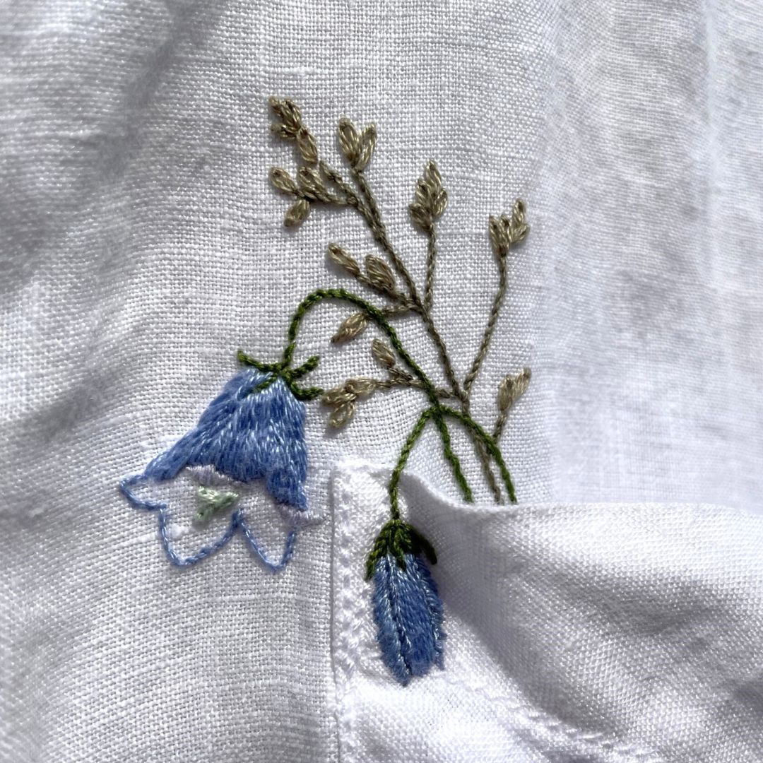 Embrioidered harebell posy in white linen shirt pocket.