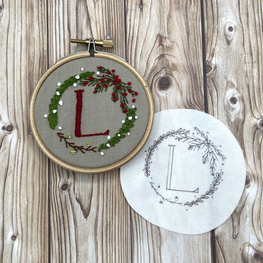 Christmas wreath embroidery sticker and finished embroidered version: a mini wreath with greenery, branches and red and white berries. Initial "L" stitched in the centre.