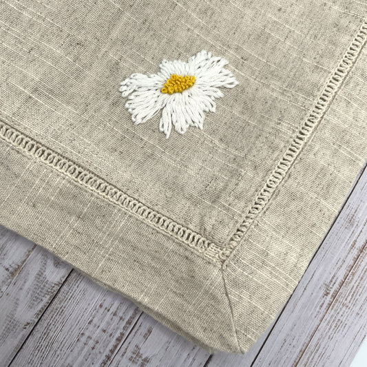 Ox eye daisy head embroidered on a natural linen napkin