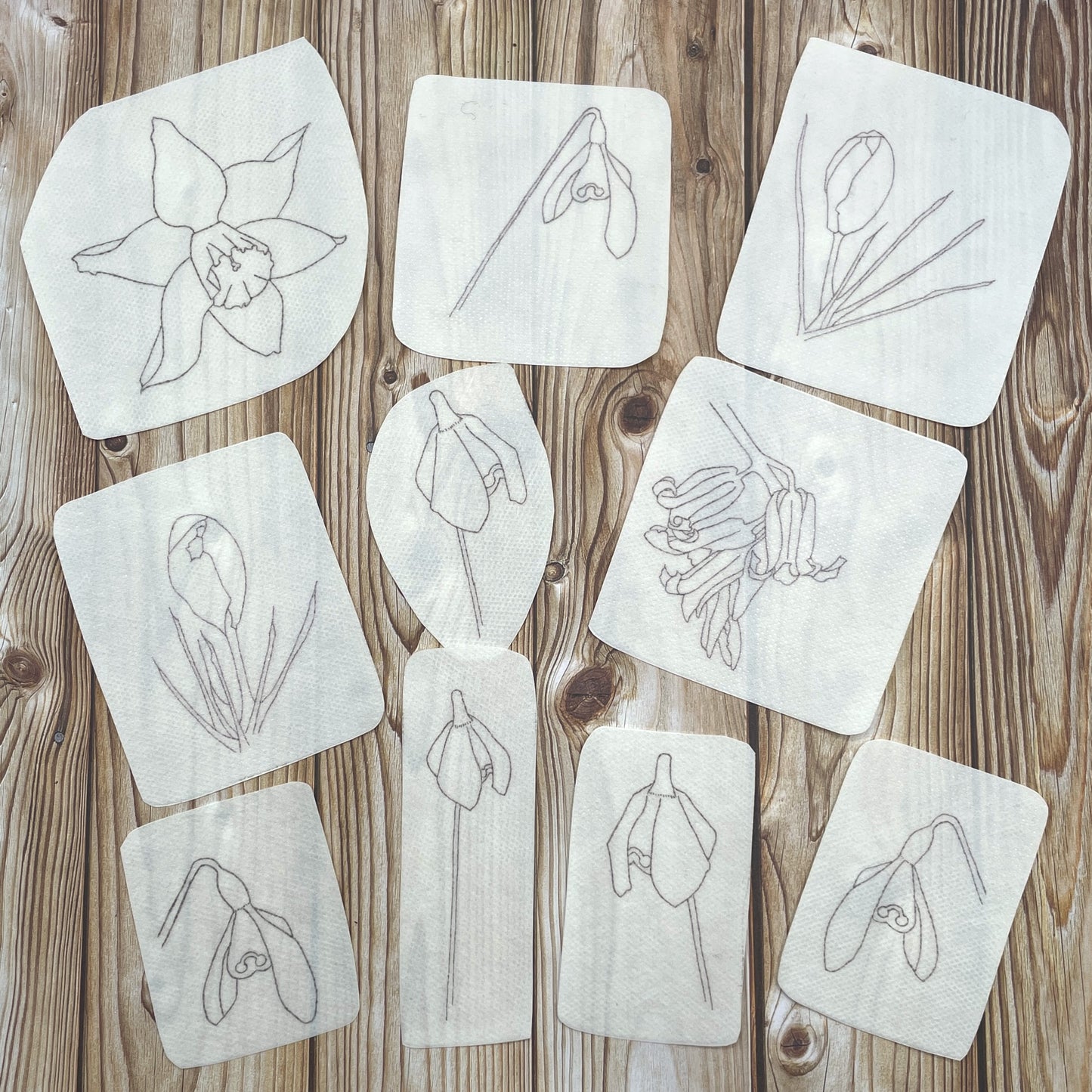 Ten spring flower embroidery stickers: one daffodil head, two crocuses, one bluebell head, six snowdrops. 