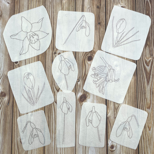 Ten spring flower embroidery stickers: one daffodil head, two crocuses, one bluebell head, six snowdrops. 